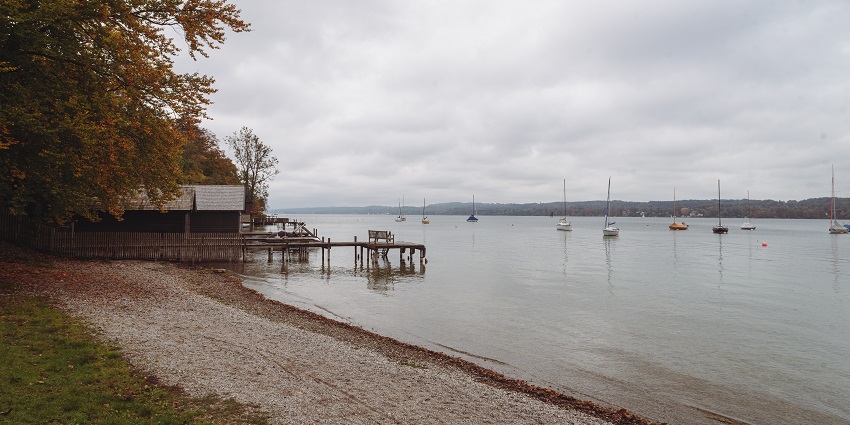 An image of Starnberger See lake with a wooden pier and multiple boats in the lake
