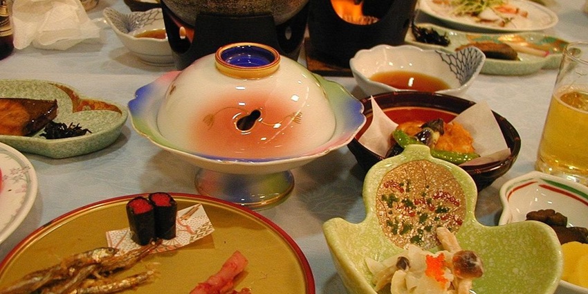 Classic Japanese dinner with many different dishes and sauces served on plates and bowls.