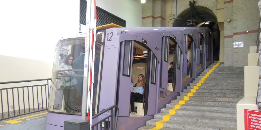 Tourists sitting inside a new car in the scenic Como-Brunate Funicular near a tunnel.