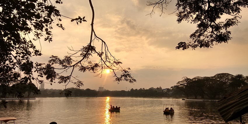 Tourists enjoying boating at Ulsoor Lake as the sun sets in the background in Bangalore