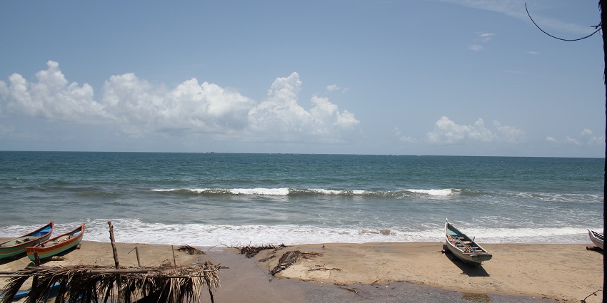 A serene image of a sandy Tarkarli beach, with several wooden boats and calm waves