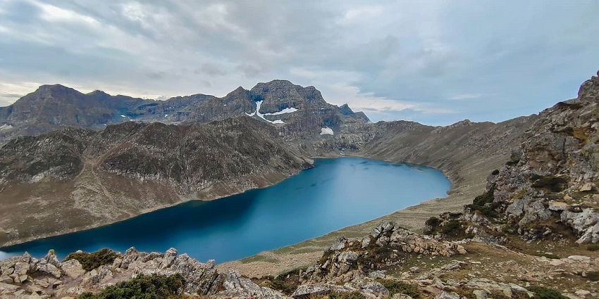 An image of Tarsar Marsar Lake surrounded by high partially snow covered mountains