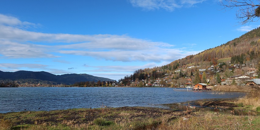 An image of Tegernsee Lake in Germany with partially dry grass, houses and buildings