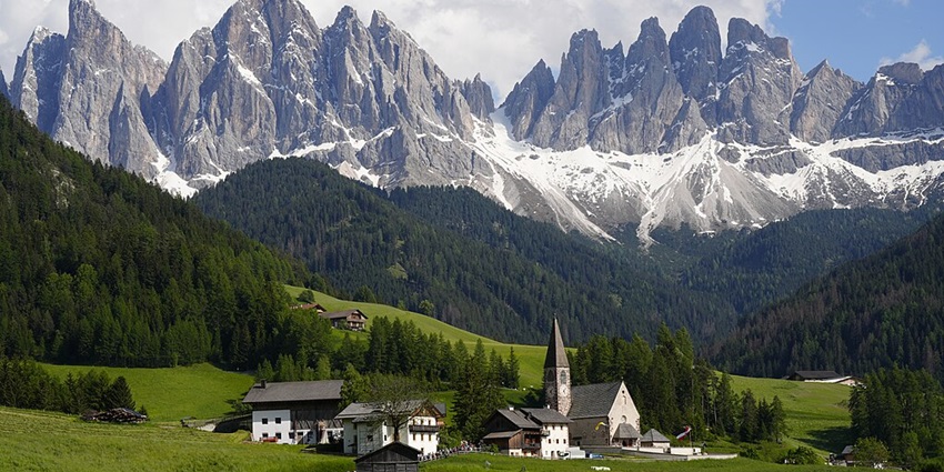 A breathtaking view of the Dolomites mountains with a small settlement in the foreground.