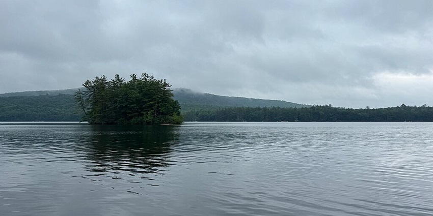 Calm waters at Crescent Lake with a background of misty mountains in Maine.