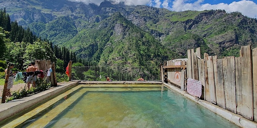 An image of the Kheerganga Springs, set in scenic mountains, with warm healing waters year-round.