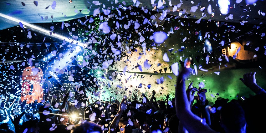An Image of people partying with a DJ and fireworks around, celebrating New Year