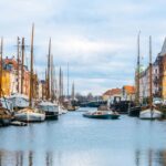 An image showing a view of boats in canal in Denmark during day time things to do in Copenhagen