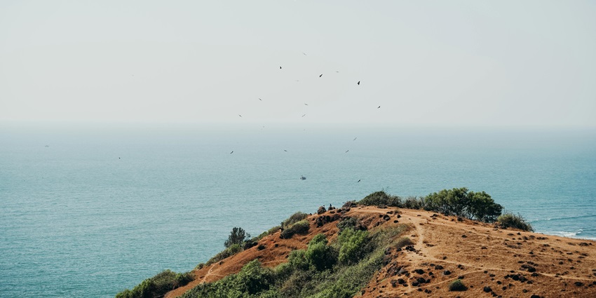 Image of Goa beach side and a rocky hill misty weather during day time