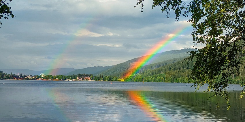 An image of a bright and vibrant double rainbow over the Titisee Lake in Germany