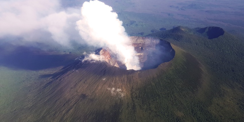 Trekkers navigating dense forests of Virunga National Park with mist-covered peaks ahead.