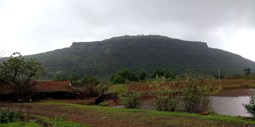 Aerial view of Tringalwadi Fort atop a mesa, overlooking Tringalwadi village and green hills