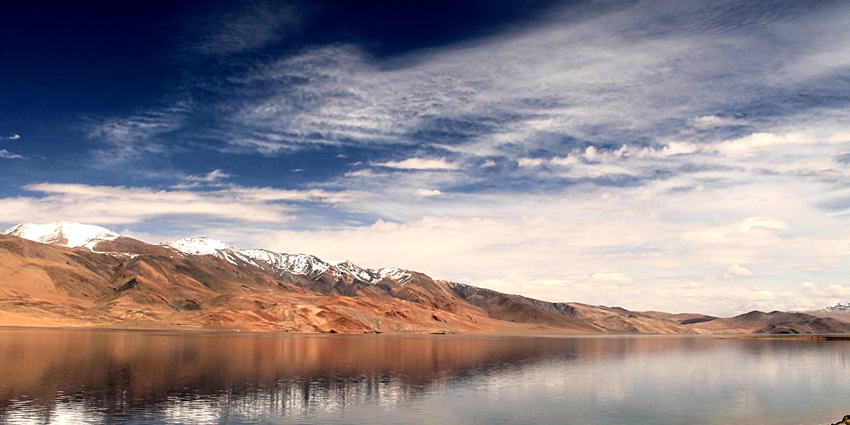 Tso Moriri Lake in Ladakh with deep blue waters, rugged mountains, and a clear sky.