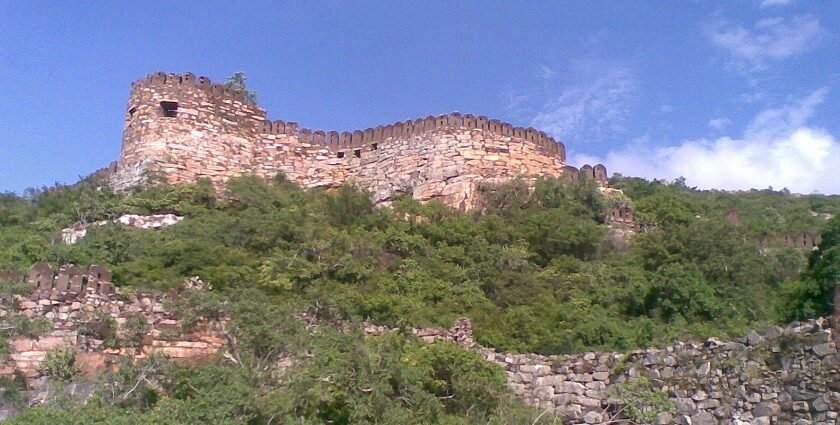 Ancient stone walls of Udayagiri Fort rising atop a lush green hill under a clear sky