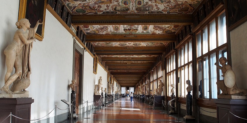 An image of Uffizi Gallery in Florence featuring sculptures, paintings, and ceilings.