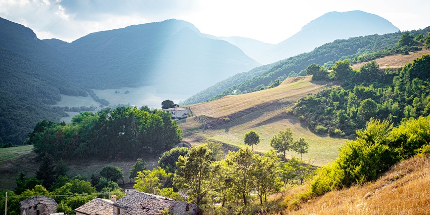 A breathtaking view of the Marche region with lush green meadows during the day.