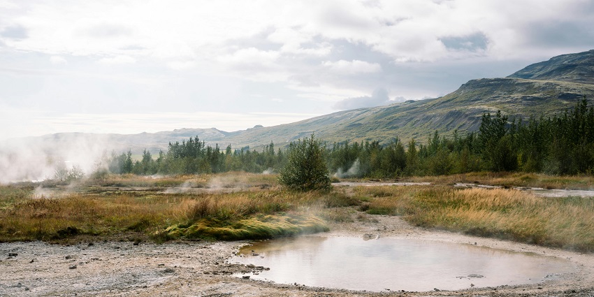 An image showing a steaming hot spring in Iceland, surrounded by a serene natural landscape.