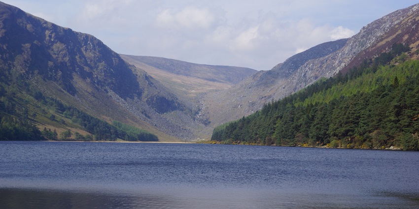 An image of Upper Lake in Glendalough, surrounded by lush green hills and forests.