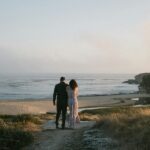 A couple standing on a path near the ocean enjoying views and celebrating Valentine's Day