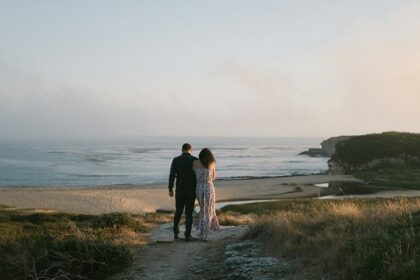 A couple standing on a path near the ocean enjoying views and celebrating Valentine's Day