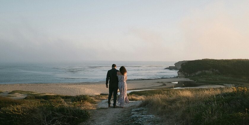 A couple standing on a path near the ocean enjoying views and celebrating Valentine's Day