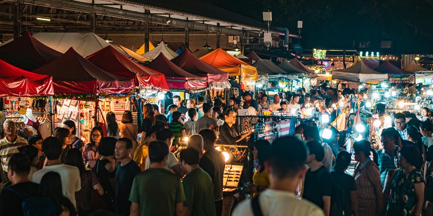 Image of a bustling night market with people strolling around and shopping