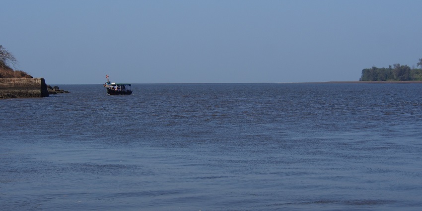 Vashishti river with a couple of boats on the river and a structure on the left side.