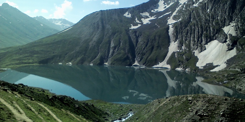 An image of Vishansar Lake in Pahalgam surrounded by greenery and snow on the mountains