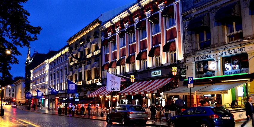 An image showing Karl Johan Gate at night in Oslo, showcasing its vibrant city lights.