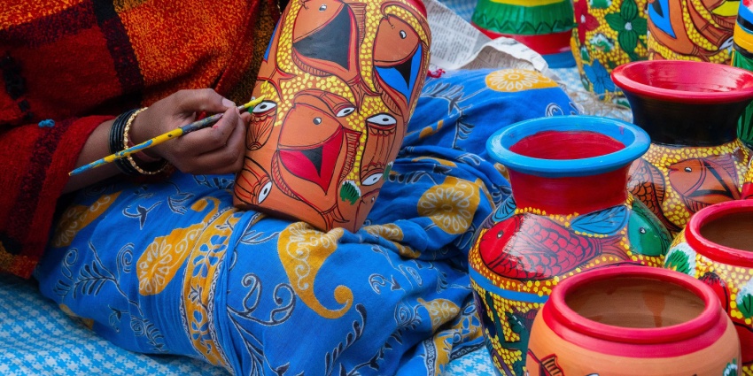 View of female Indian artist painting colorful terracotta pots for sale during Taj Mahotsav Agra.