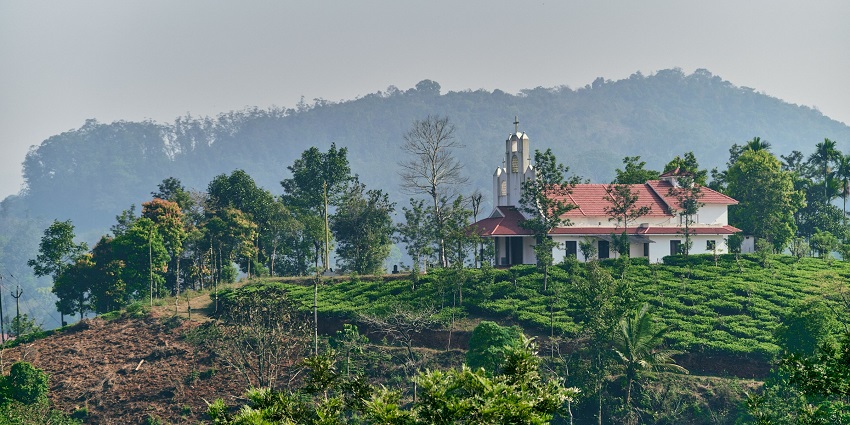 An image of the beautiful scene of a road amid the stunning green hills of Wayanad.