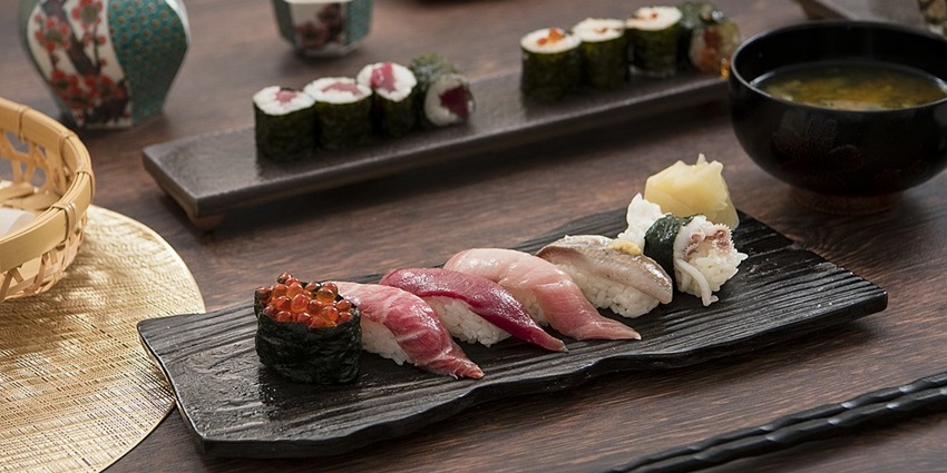 Classic Japanese cuisine with sushi served on a wooden plate and soup and chopsticks.