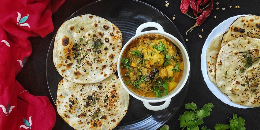 Odisha dish of aloo Rayagada with tandoori chapatis served on a black plate and a red cloth