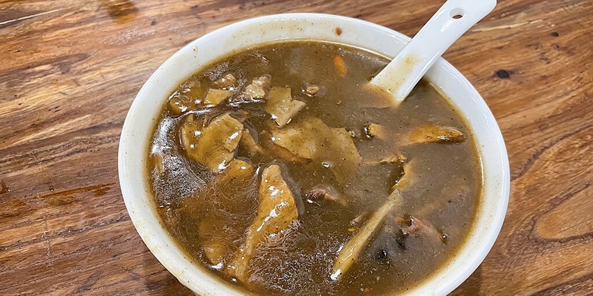 Bowl of Henan-style Hulatang soup with noodles, vegetables, and herbs in a rich broth