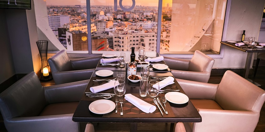 An image showing a rectangular brown wooden table in a restaurant setup with elegant decor