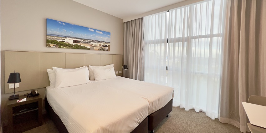 A lavish executive suite room with a view of a river from a glass window.