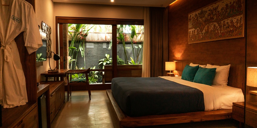 Luxury hotel room with a wood bed frame, and a private pool outside the glass doors.