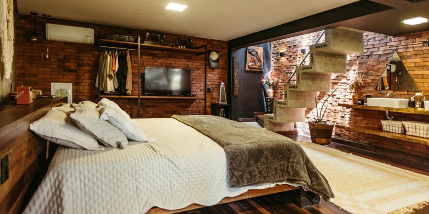 Image of cosy interior of a hotel room with a bed, and hanging clothes and wooden walls