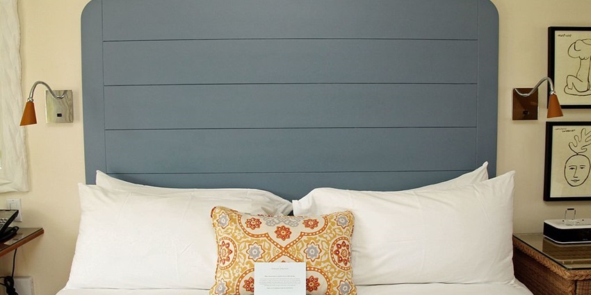 Hotel room with a bed, multiple pillows, lamps on both sides of the bed and paintings
