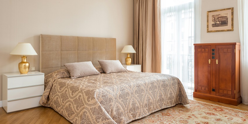 A styled bedroom with a large bed featuring a comforter, flanked by nightstands and lamps