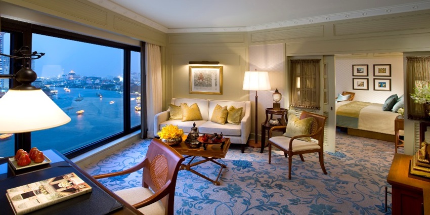 A glimpse of lavish executive suite room with a view of a river from a glass window.