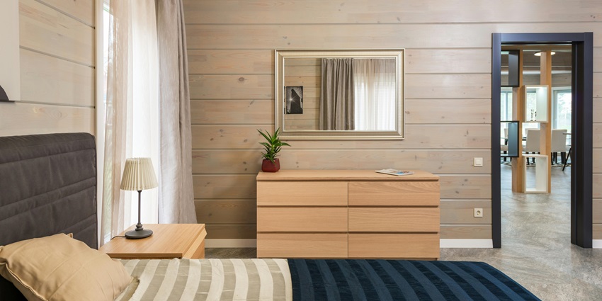 An image showing a modern hotel bedroom with a neatly made bed and stylish furniture.