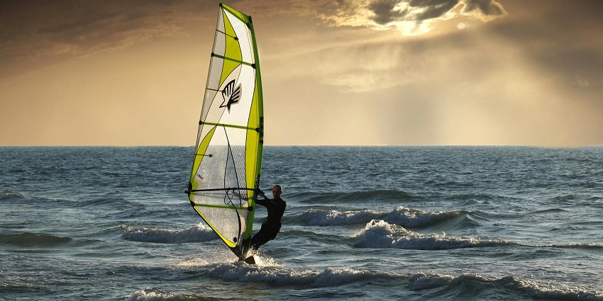 An image of a windsurfer skillfully gliding across the surface of a lake in Lonavala.