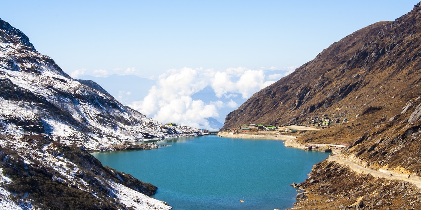 An image of beautiful Turquoise blue Tsomgo Lake is surrounded by snow-capped mountains.