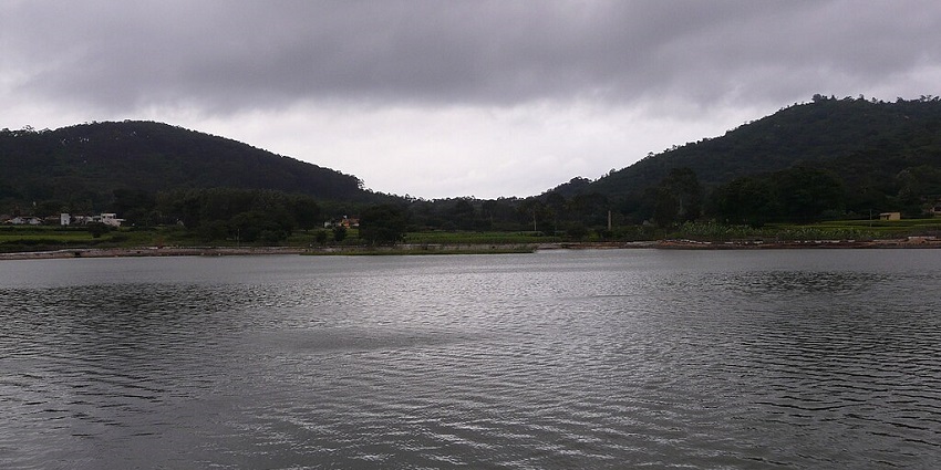 An image showing a lake surrounded by hills and trees at Yelagiri, with boats on the water