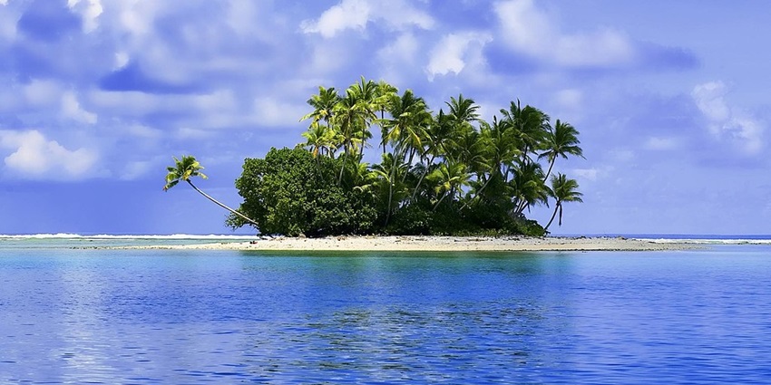 The aerial view of an island under a clear sky, situated in the middle of a sea.