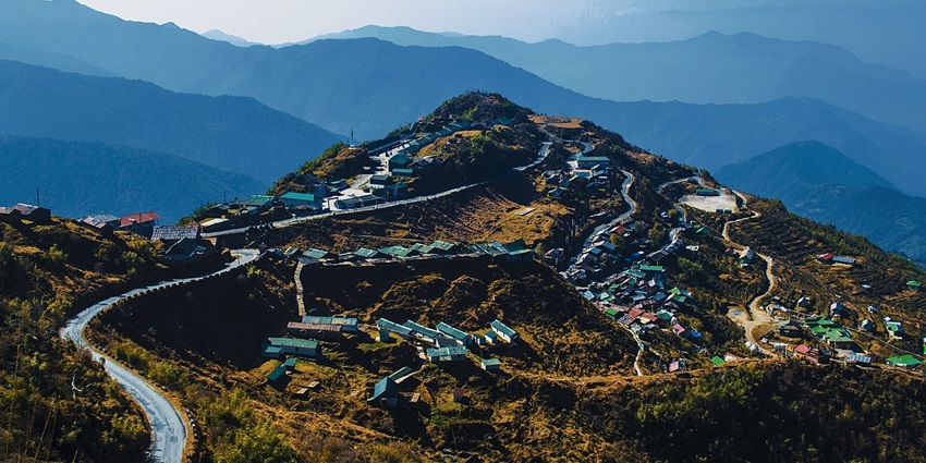 A mesmerising view of Zuluk Village with trails of misty mountains in the background.