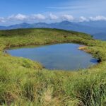 Chembra Lake, a unique heart shaped lake in India with distant mountains under clouds.