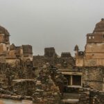 An image of Chittorgarh Fort showing ancient stone structures under a cloudy sky.