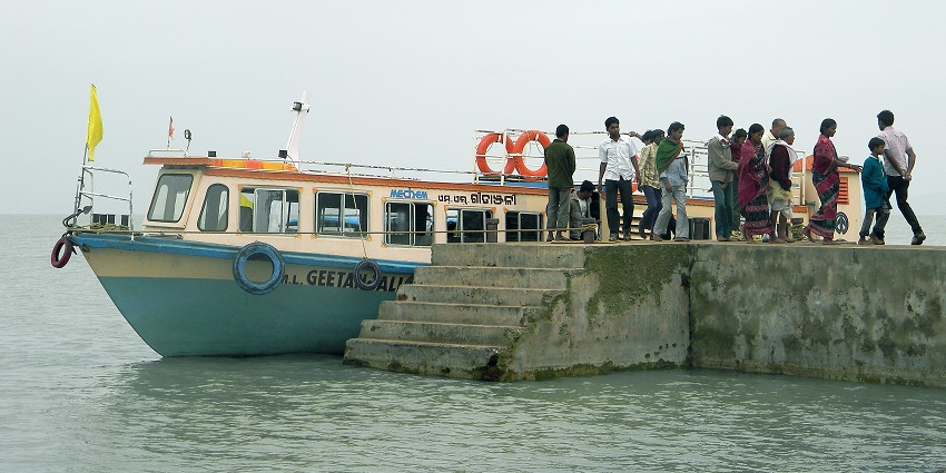An image of a boat dotting the surface of the largest brackish water lake in India.
